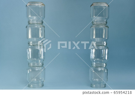 Two vertical parallel rows of glass jars on a blue background. Two vertical parallel rows of glass jars on a blue background. 65954218