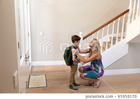 Caucasian woman kneeling with her son in the hallway Caucasian woman kneeling with her son in the hallway 65958170