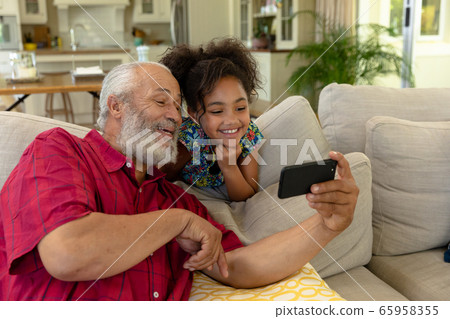 Senior mixed race man with her granddaughter at home 65958355