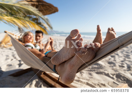 Caucasian couple lying on a hammock at the beach. Caucasian couple lying on a hammock at the beach. 65958378
