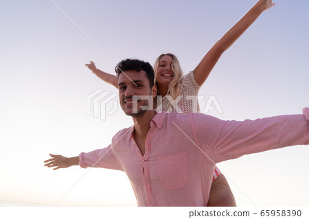 Caucasian couple enjoying time at the beach during the sunset 65958390