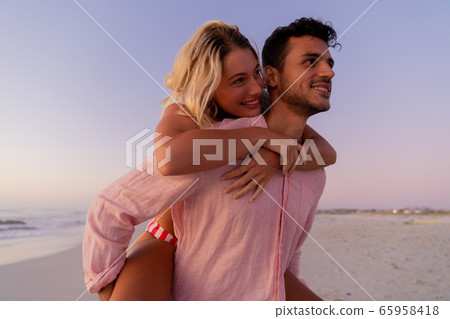 Caucasian couple enjoying time at the beach during the sunset 65958418