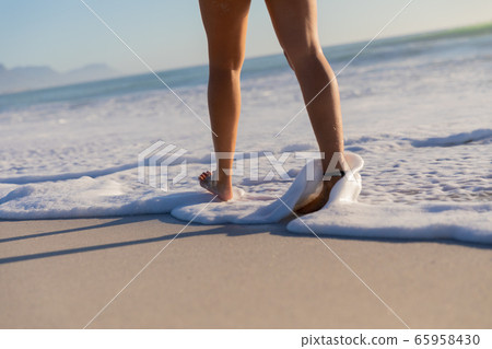 Caucasian woman walking towards the sea at the beach 65958430