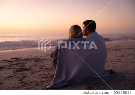Caucasian couple enjoying time at the beach during the sunset 65958685