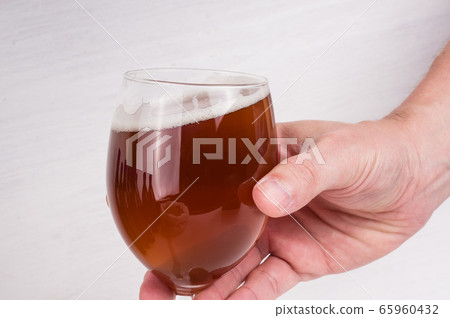 male hand holding a glass of homemade craft beer 65960432
