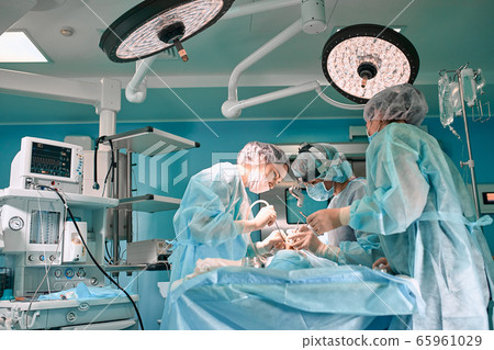 Modern surgery in a technologically advanced hospital. Bright room of intensive care. Doctors and assistants working in the operating room save lives. 65961029