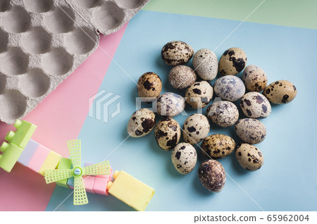 heap of quail eggs and toy on color background. heap of quail eggs and toy on color background. 65962004