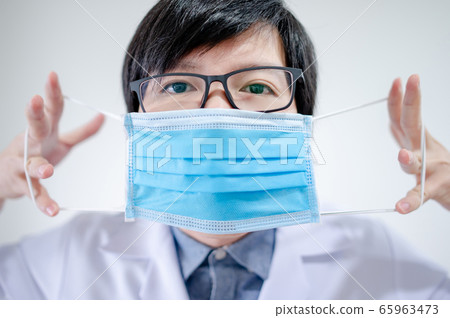 Doctor showing how to wear surgical mask Doctor showing how to wear surgical mask 65963473