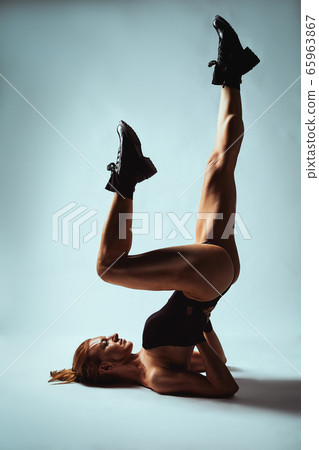 Girl in a black body up nagami on a gray background. A woman with a beautiful body poses upside down in dark boots. Fashion, copy space, gray background Girl in a black body up nagami on a gray background. A woman with a beautiful body poses upside down in dark boots. Fashion, copy space, gray background 65963867