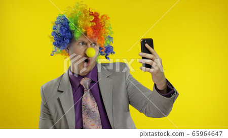 Clown businessman entrepreneur boss in wig making selfies using smartphone 65964647