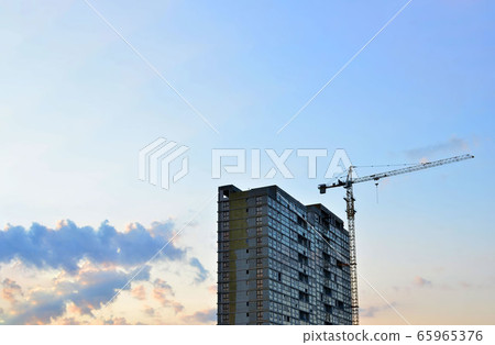 Tower crane and new residential high-rise buildings at a huge construction site on sunset background 65965376