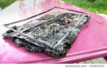 Broken laptop computer spoiled by flame melted 65965507