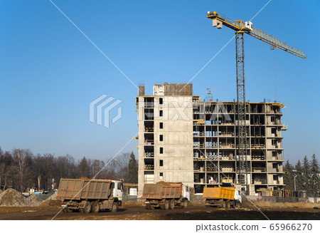 Heavy dump trucks and hydraulic luffing jib tower cranes works at a construction site 65966270