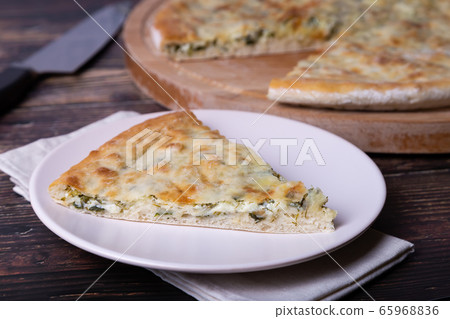 Ossetian pie with cheese and herbs (dill, parsley, scallion). Traditional Ossetian baking. Ossetian pie with cheese and herbs (dill, parsley, scallion). Traditional Ossetian baking. 65968836
