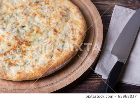 Ossetian pie with cheese and herbs (dill, parsley, scallion). Traditional Ossetian baking. Ossetian pie with cheese and herbs (dill, parsley, scallion). Traditional Ossetian baking. 65968837