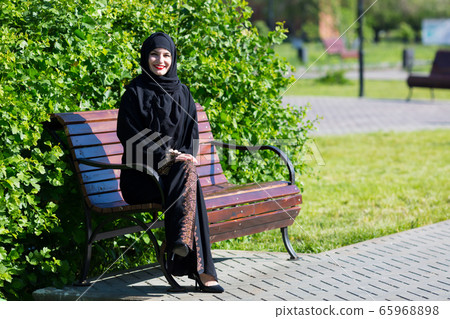 A beautiful young muslim woman is sitting on a A beautiful young muslim woman is sitting on a 65968898