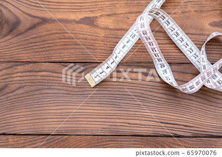 White measuring tape of a tailor lies in corner on 65970076