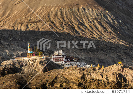 The Maitreya Buddha statue with Himalaya mountains in the background from Diskit Monastery or Diskit Gompa, Nubra valley, Leh Ladakh The Maitreya Buddha statue with Himalaya mountains in the background from Diskit Monastery or Diskit Gompa, Nubra valley, Leh Ladakh 65971724