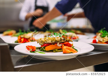 Meat dish with vegetables for catering. Lots of plates. 65972023