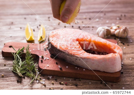 Squeezing fresh lemon juice on the fillets of fish. Cooking salmon steak. Squeezing fresh lemon juice on the fillets of fish. Cooking salmon steak. 65972744