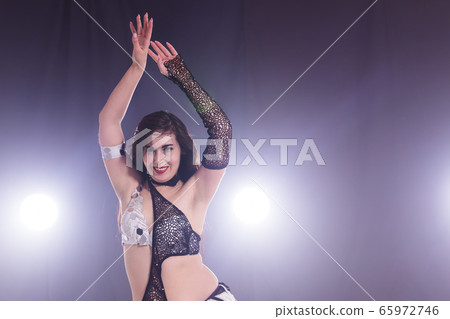 Young woman dancing in Tribal Fusion style. Belly dance on the stage. Young woman dancing in Tribal Fusion style. Belly dance on the stage. 65972746
