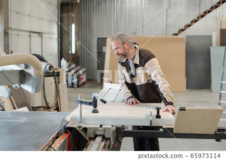 Senior worker of furniture producing factory fixing board on workbench Senior worker of furniture producing factory fixing board on workbench 65973114