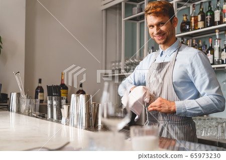 Handsome bartender wiping glass with special rag Handsome bartender wiping glass with special rag 65973230