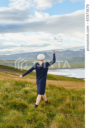 My beautiful Iceland. Rear view of young happy female tourist wearing dress and wool hat enjoying amazing Icelandic landscape My beautiful Iceland. Rear view of young happy female tourist wearing dress and wool hat enjoying amazing Icelandic landscape 65973676