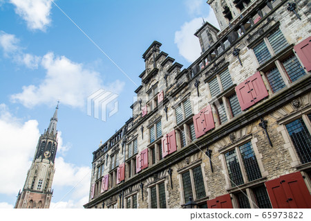 Cityscape of Delft, the Netherlands: historic brick buildings and tall cathedral 65973822