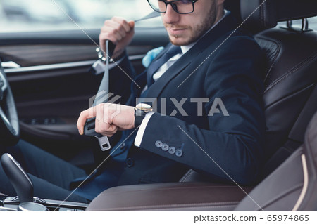 Guy Putting On Seat Belt Sitting In Luxury Car Guy Putting On Seat Belt Sitting In Luxury Car 65974865