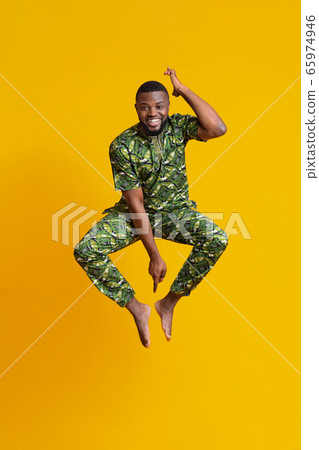 Barefoot black guy in african costume jumping up 65974946