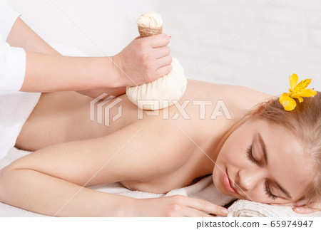 Ayurvedic procedure. Professional doing massage with herbal bags for girl 65974947