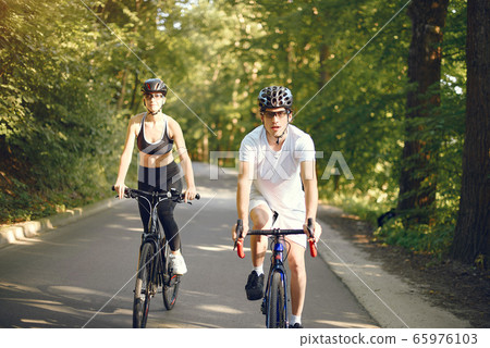 Sports couple riding bikes in summer forest Sports couple riding bikes in summer forest 65976103