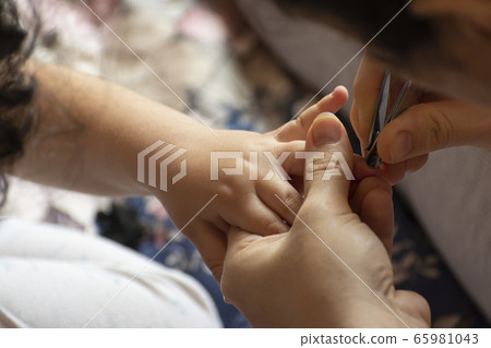 Young mother cuts a small child fingernails by Young mother cuts a small child fingernails by 65981043