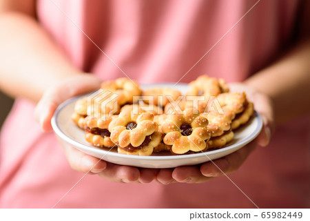 Cracker with pineapple jam (flower shape) on plate holding by woman hand, Thai snack 65982449