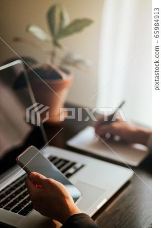 office worker browsing phone and laptop indoors office worker browsing phone and laptop indoors 65984913