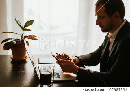 office worker browsing phone and laptop during office worker browsing phone and laptop during 65985264