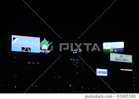 Night view in front of Shin-Osaka station including Daikin Kogyo's "Pichon-kun" that turned green (light blue) related to the new Corona 65985590