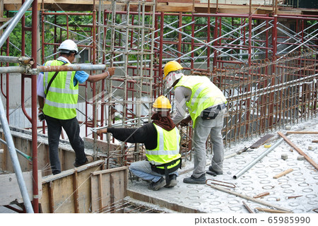 MALACCA, MALAYSIA -MAY 27, 2016: Construction workers fabricating steel reinforcement bar at the construction site in Malacca, Malaysia. The reinforcement bar was tied together using tiny wire.   65985990