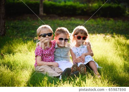 Smiling kids at the garden in sunglasses Smiling kids at the garden in sunglasses 65987898