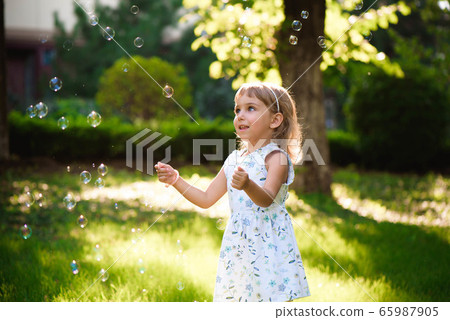 Portrait of funny lovely little girl blowing soap bubbles 65987905