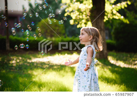 Portrait of funny lovely little girl blowing soap bubbles 65987907