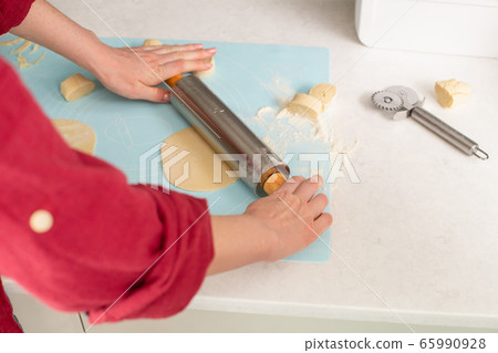 Woman roll dough with pin on mat 65990928