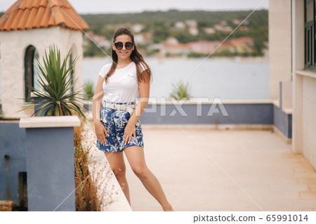 Stylish beautiful woman walking near the pier by the sea. Woman walking alone in the morning. End of quarantine 65991014