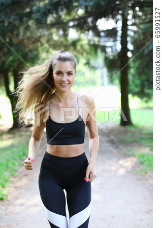 Beautiful girl in sportswear runs in summer park 65991527