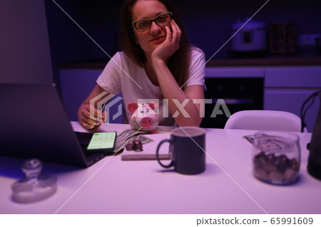 Woman sitting in kitchen front laptop makes budget Woman sitting in kitchen front laptop makes budget 65991609