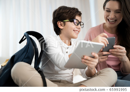 Kid and his parent with gadgets sitting at home Kid and his parent with gadgets sitting at home 65991995
