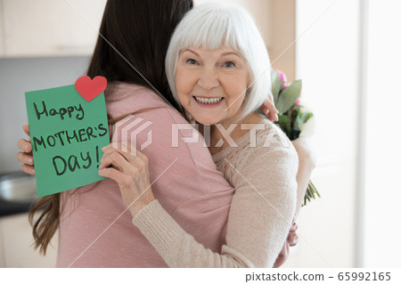 Dark-haired young female hugging her pleased mother 65992165