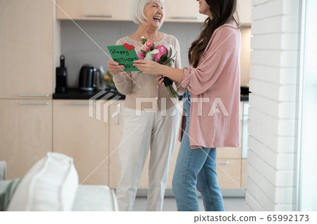 Young woman congratulating her parent on the holiday 65992173