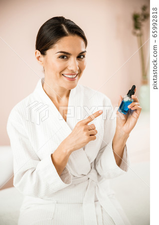 Joyful woman demonstrating her beauty treatment in bottle Joyful woman demonstrating her beauty treatment in bottle 65992818